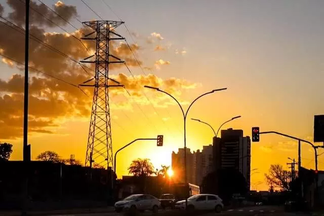 Sol entre prédios e vegetação na região da Avenida João Arinos, em Campo Grande (Foto: Henrique Kawaminami)